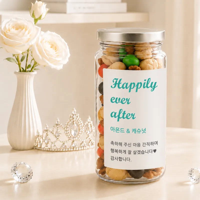 흰 장미와 티아라 옆에 놓인 견과류 답례품 보틀, 'Happily ever after'와 아몬드·캐슈넛 감사 문구 라벨