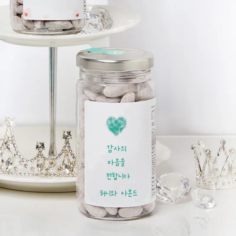 블루프롬더플래닛 허니버터아몬드 답례품 보틀 제품 사진, 하트구름 라벨이 붙은 보틀에 허니버터아몬드가 담겨 있다